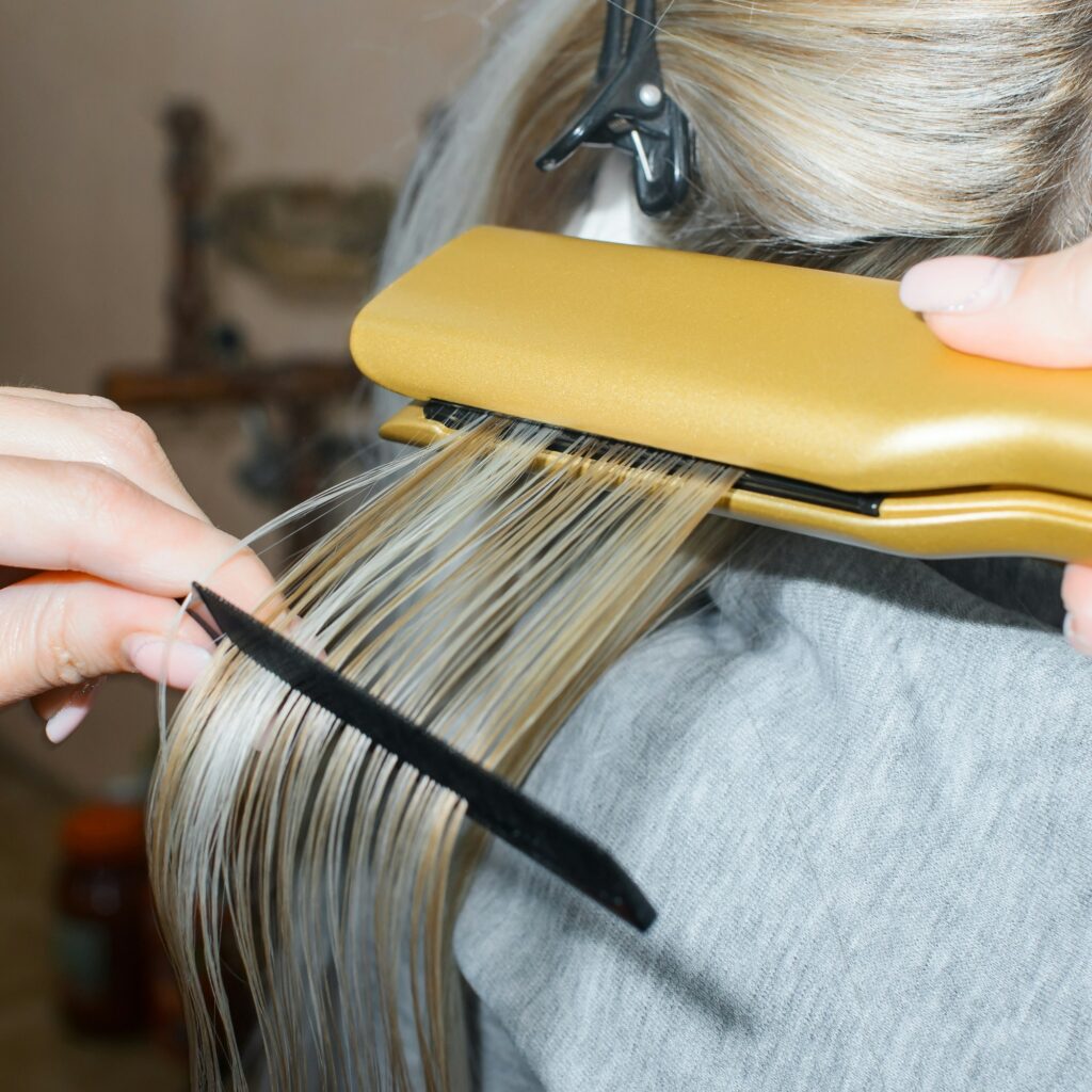 Keratin hair straightening with a professional iron. Hairdresser performing hair treatment.