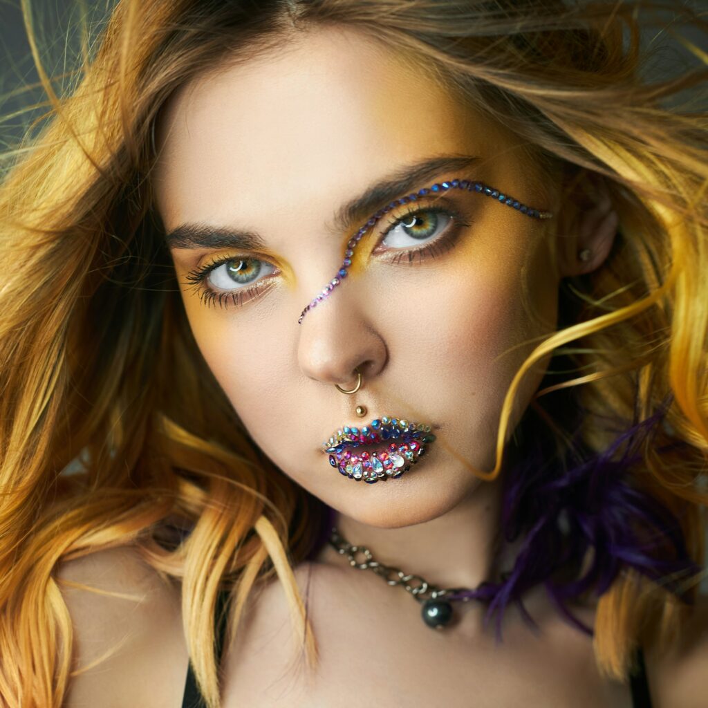 Woman with creative yellow coloring hair and makeup with rhinestones, purple strands of hair second